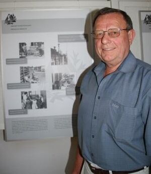 Bruno Helgert vor dem Ausstellungsplakat "Ankunft in Deutschland"